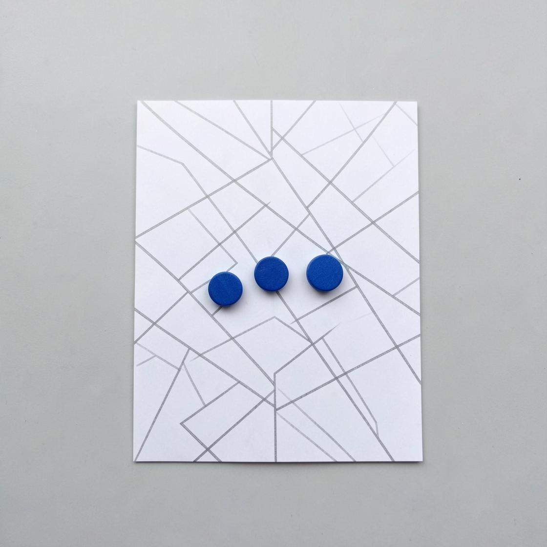 Three plain blue tokens on an unlabelled abstract street grid drawn on white paper.
