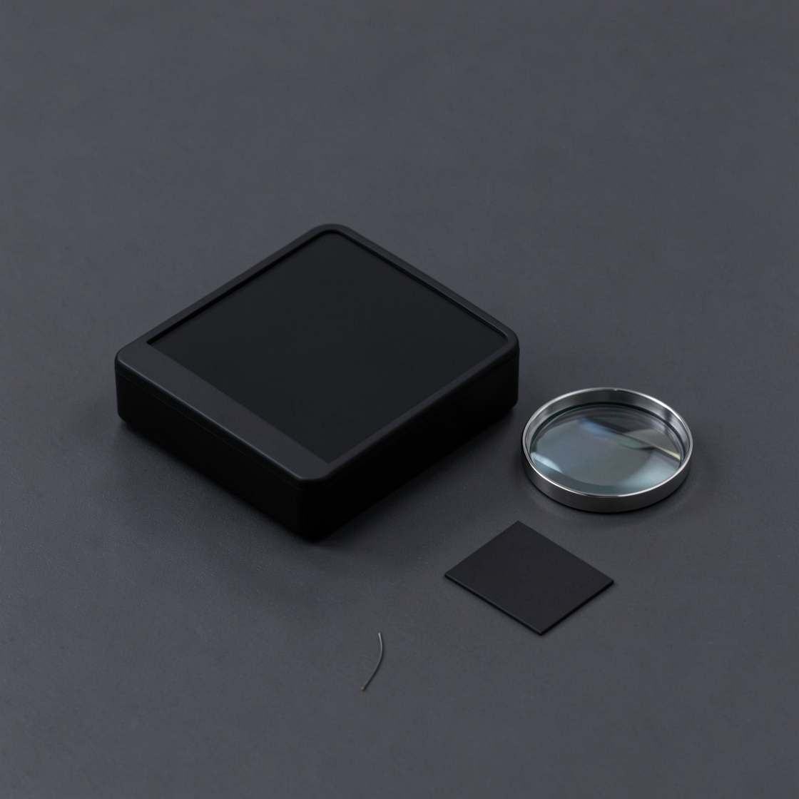 Conceptual blank electronic device beside an inspection lens, a black tile and a loose wire