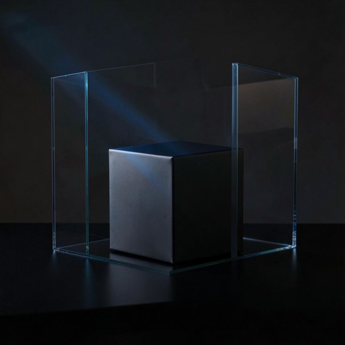 An unmarked metal cube framed by transparent glass panels on a dark surface