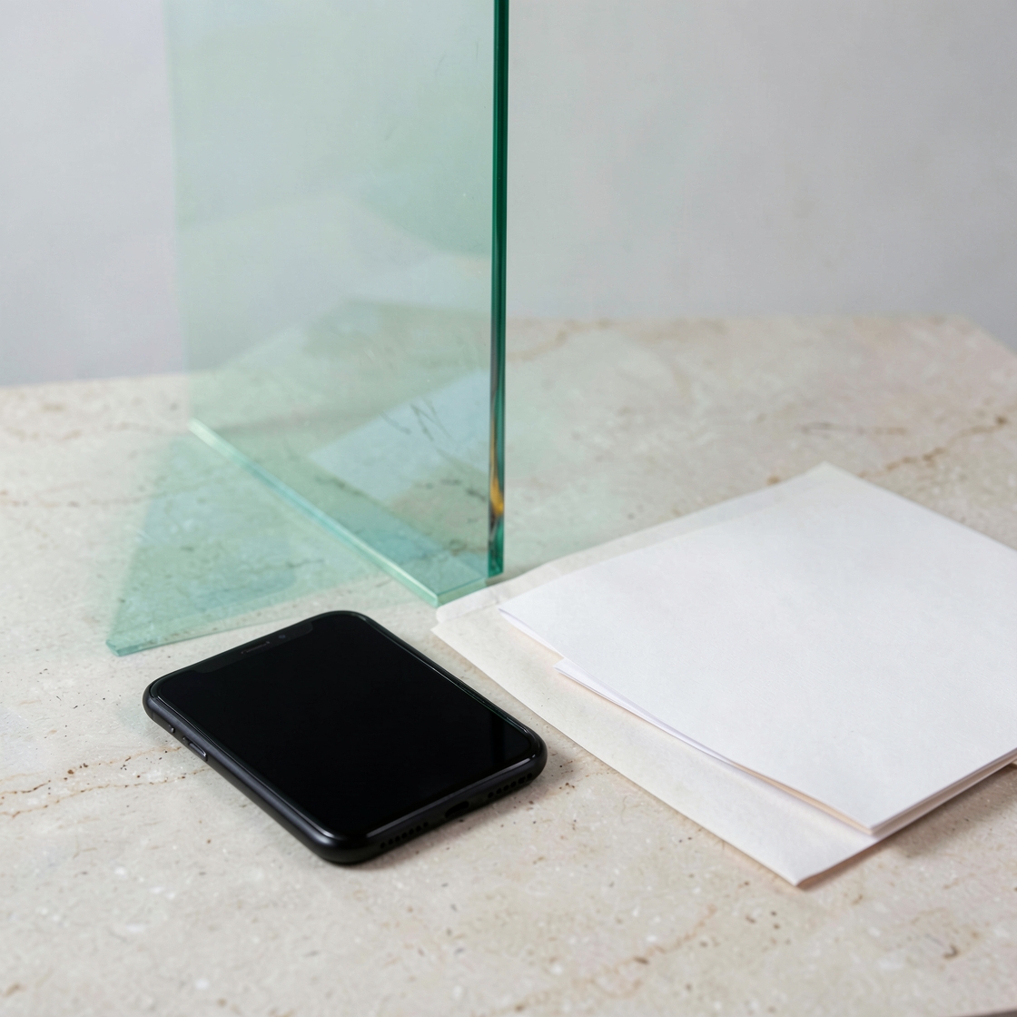 An unbranded phone with a dark screen beside a glass divider and blank papers