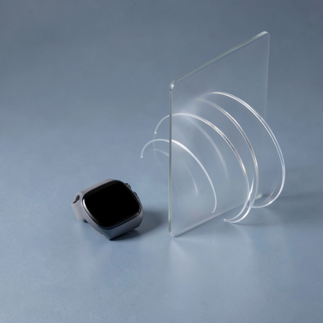 Conceptual watch with a blank display beside glass sound-wave arcs