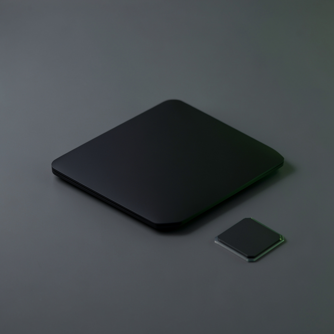 Closed unbranded black laptop and a blank square processor package on a grey surface